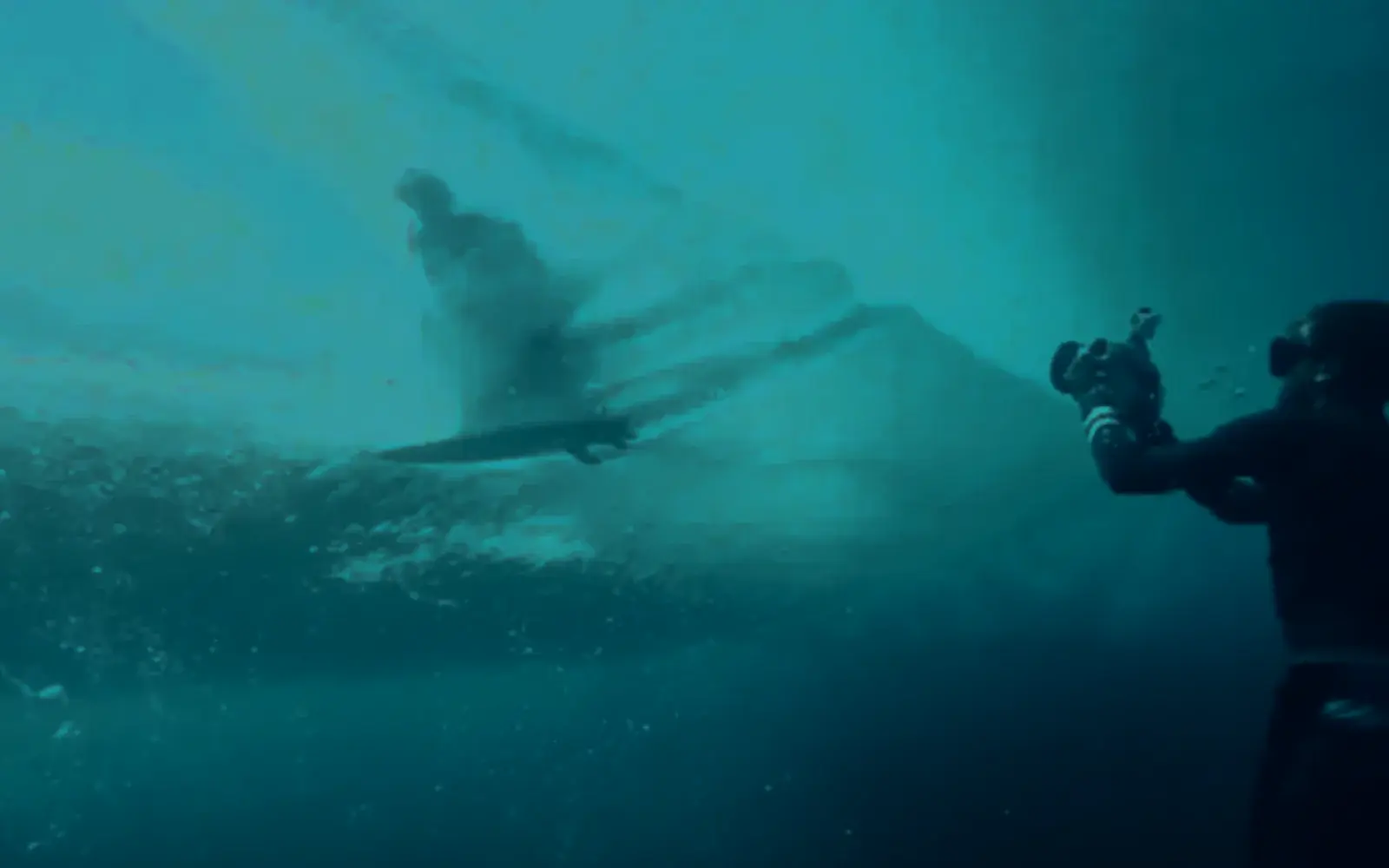Underwater figure reaching upward through open water