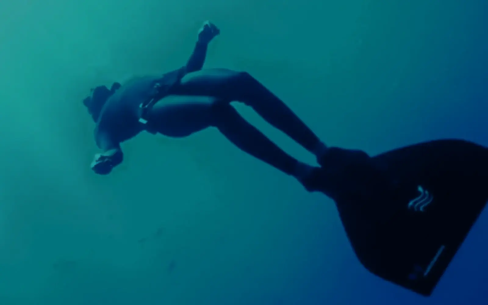 Free diver moving through deep blue water