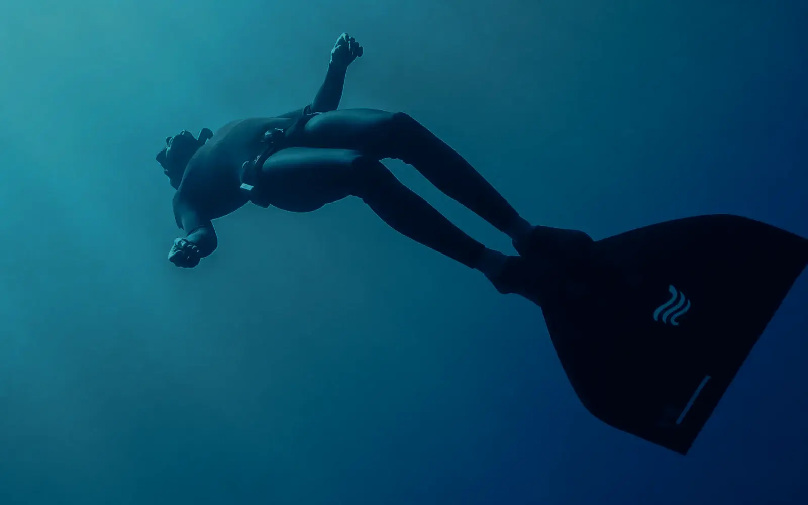 Free diver moving through deep water beneath the surface